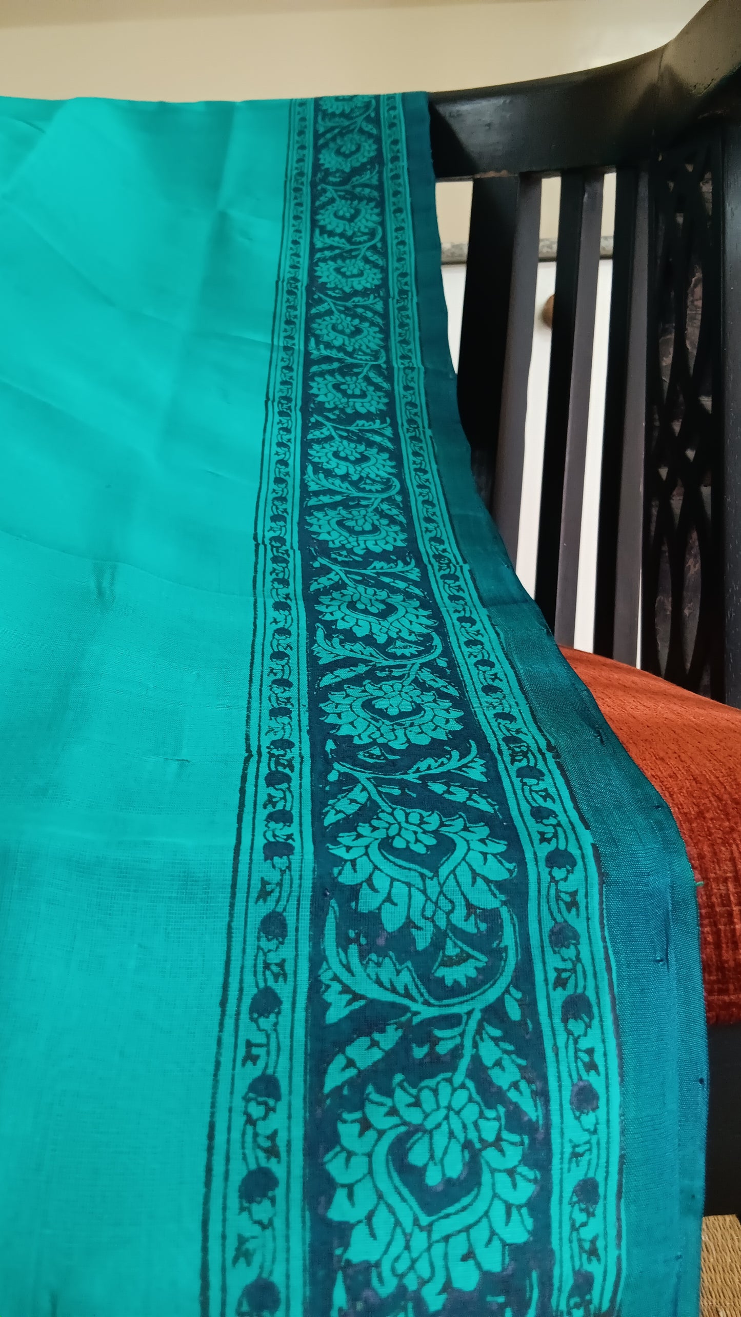 Close up view of the traditional motifs block printed on the border of a simple hand woven, blue, daily wear, silk cotton saree