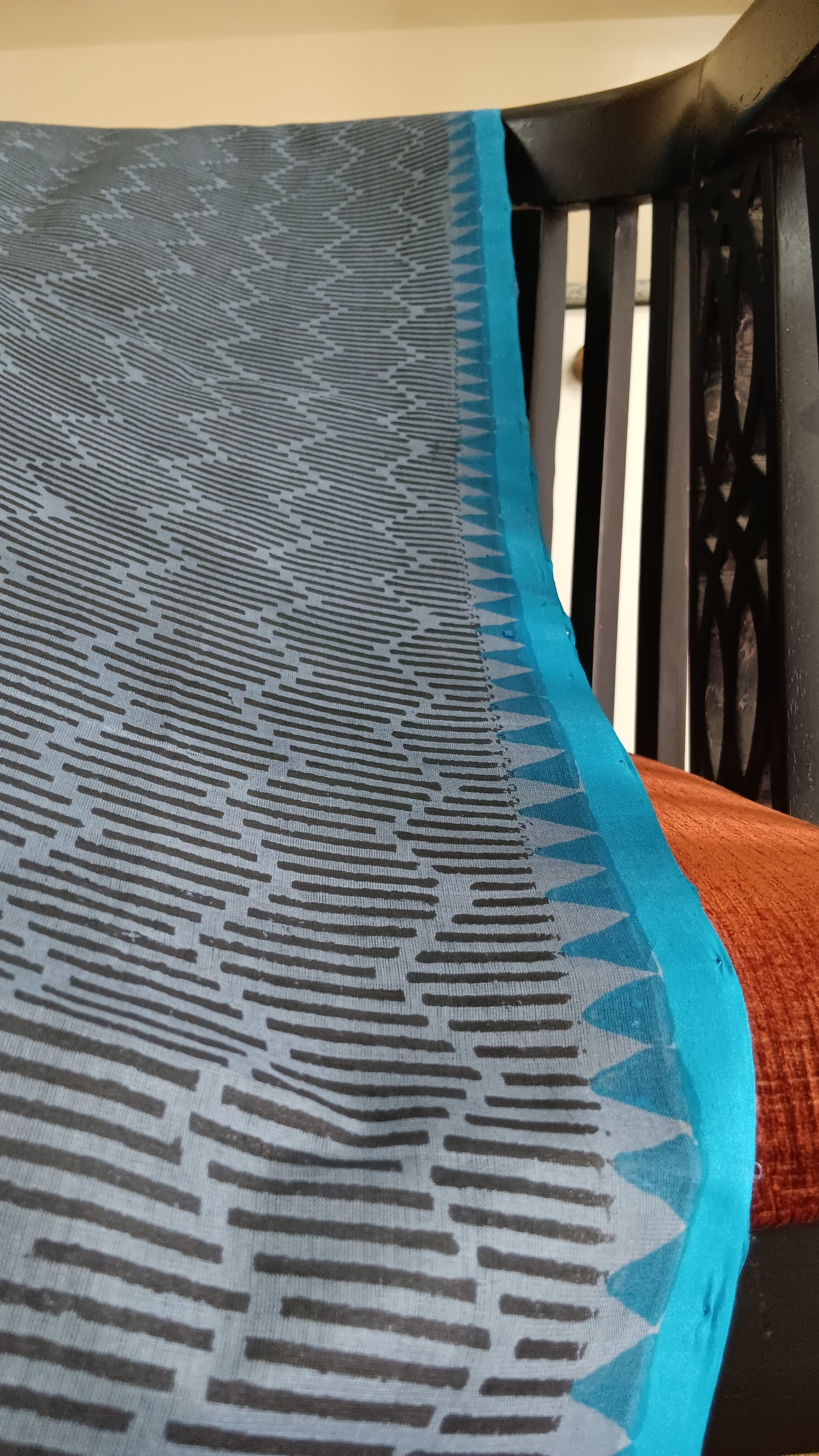 Close up view of the temple motifs block printed in blue along the blue border of a simple hand woven, grey, daily wear, silk cotton saree