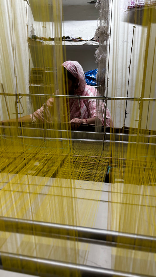 Lady at her pitloom weaving a yellow kota saree