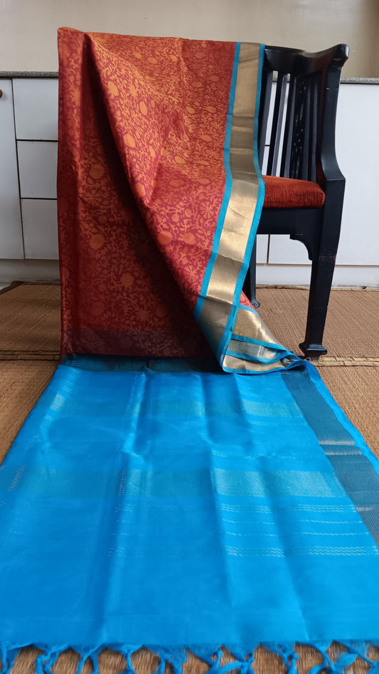 hand woven and block printed silk cotton saree with a rust body and blue pallu