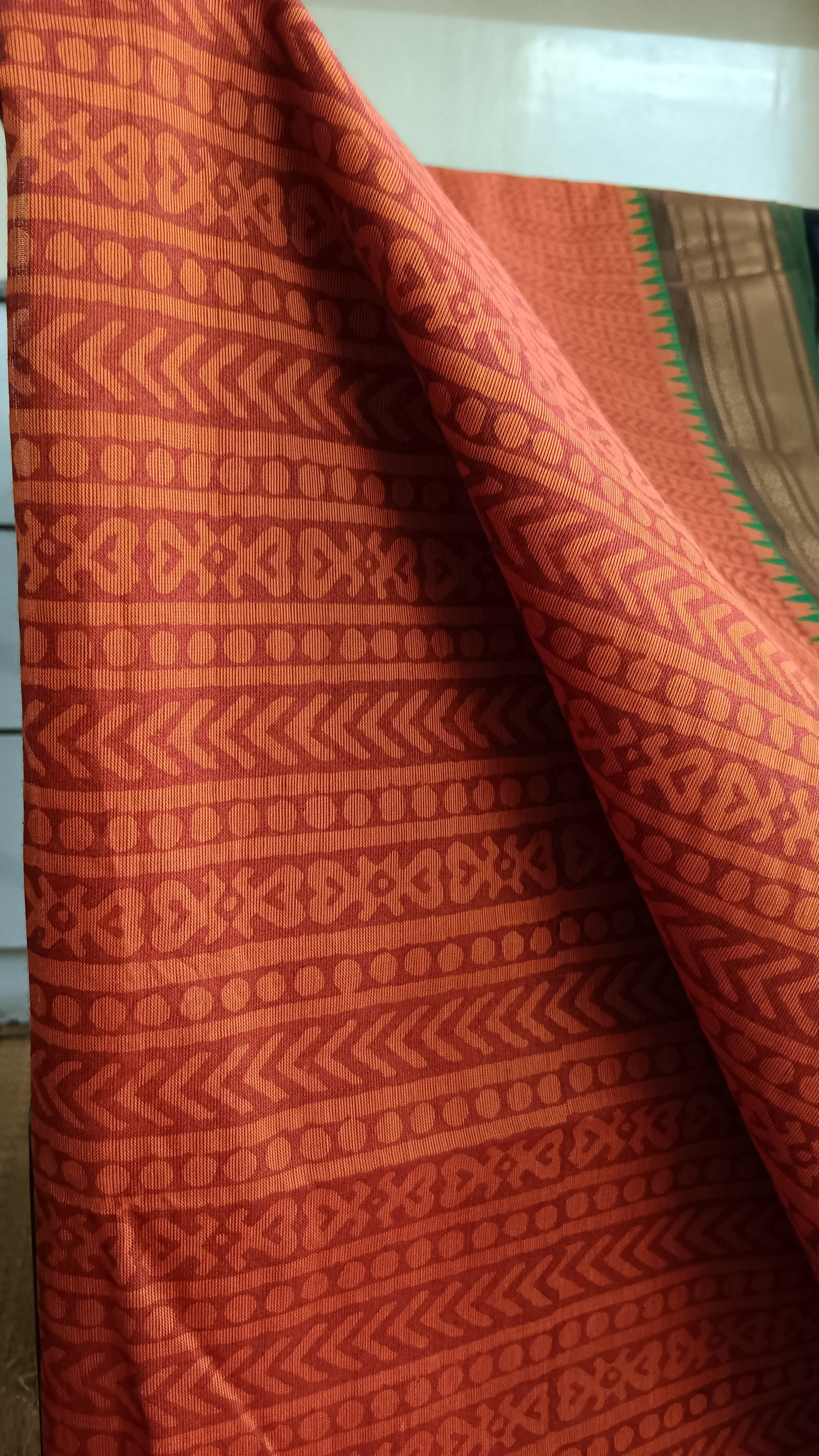 Close up view of the geometric patterns block printed on the brick red body of a function wear cotton saree