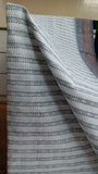 Close-up view of the bold geometric patterns printed in bluish-grey on the off-white cotton saree body.