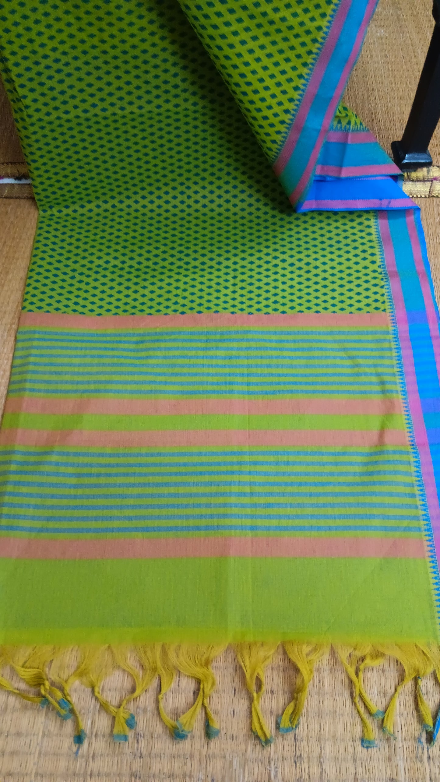 Top view of the saree's pallu in refreshing green cotton, showcasing a continuation of the geometric print and a touch of the blue border