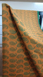 Close-up view of elegant paisley motifs block printed in dark green on the mustard cotton saree body.