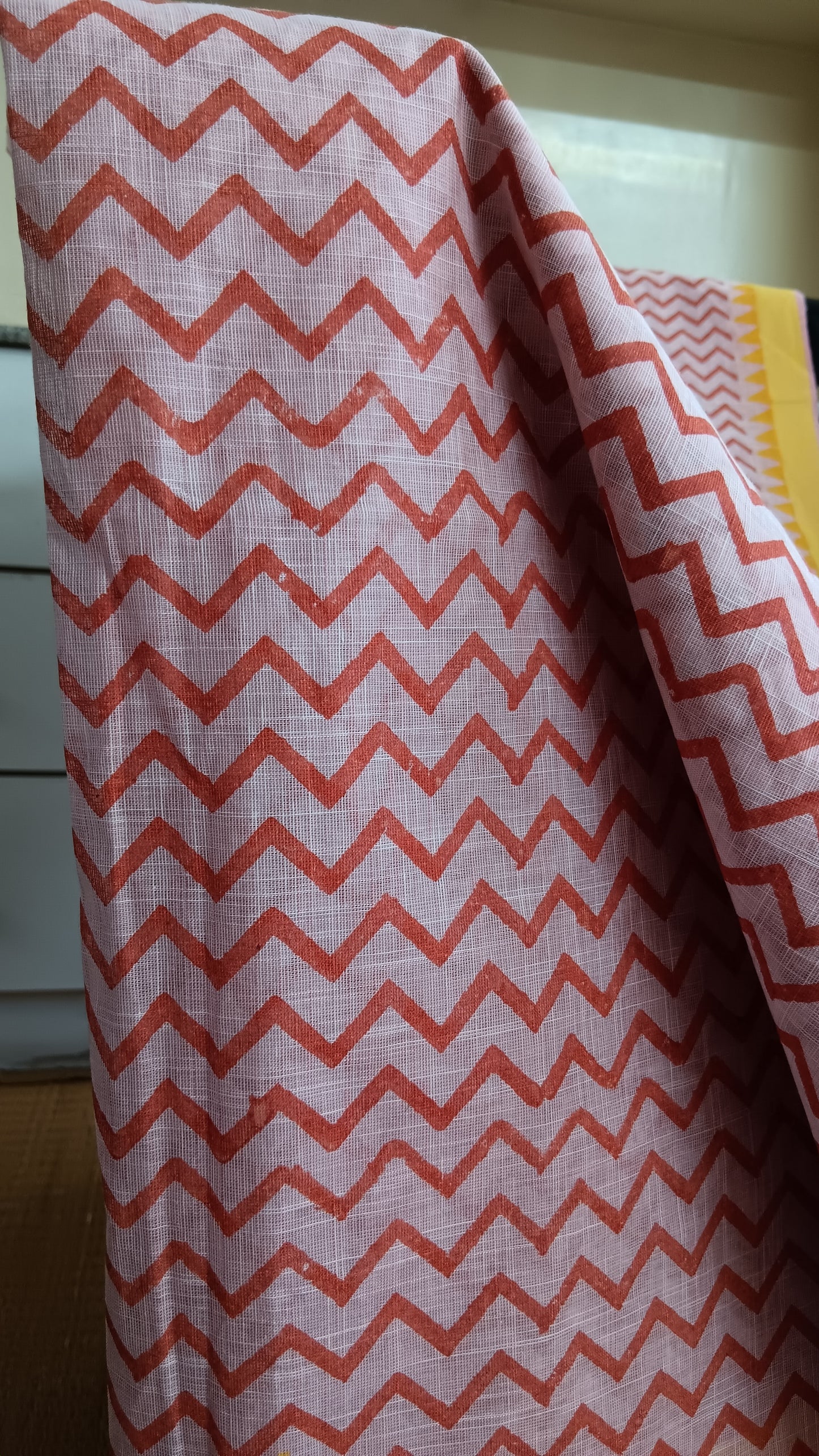 close up view of the chevron pattern block printed on the body of a pink cotton saree for daily use