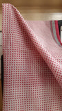 CLose up view of the body of a kota cotton saree that has been block printed with pink delicate geometric motifs