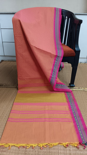Delicate blush pink cotton saree featuring a contrasting dark pink border and subtle geometric block prints in a deeper pink shade. Perfect for a touch of serenity and calmness for everyday wear.