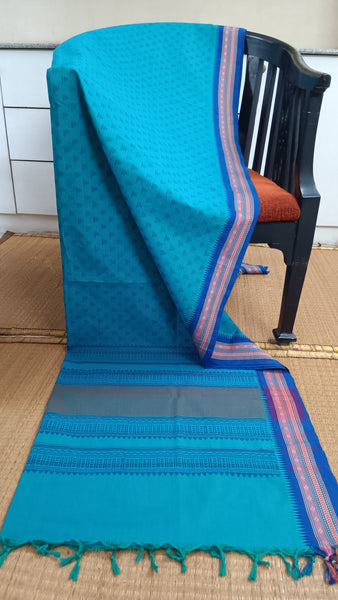 Refreshing turquoise cotton saree featuring a contrasting deep blue border and small temple motifs block printed in a darker turquoise shade. Perfect for a touch of cultural charm and summer vibes.