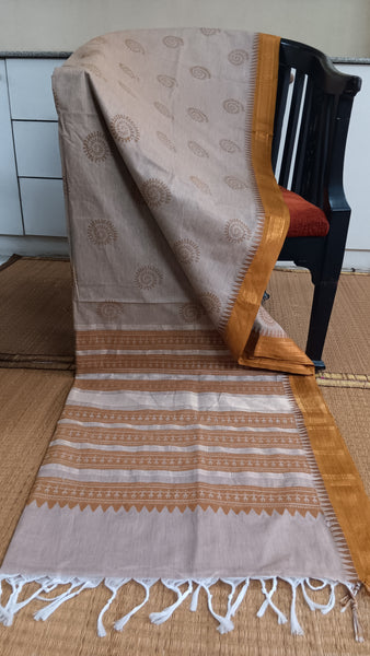 Elegant beige cotton saree with a mustard yellow temple border featuring warli motifs. Perfect for sophisticated family functions.
