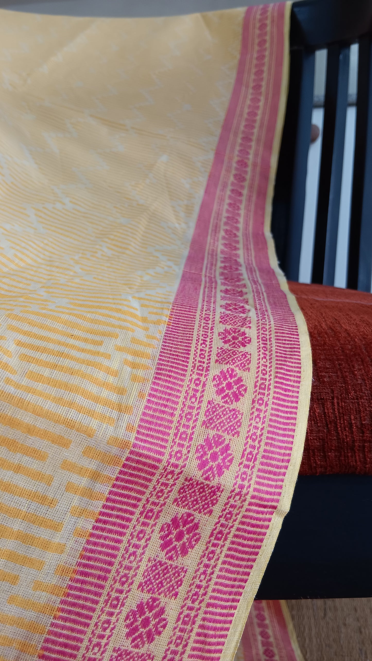 close up view of the woven pink border of a yellow cotton saree