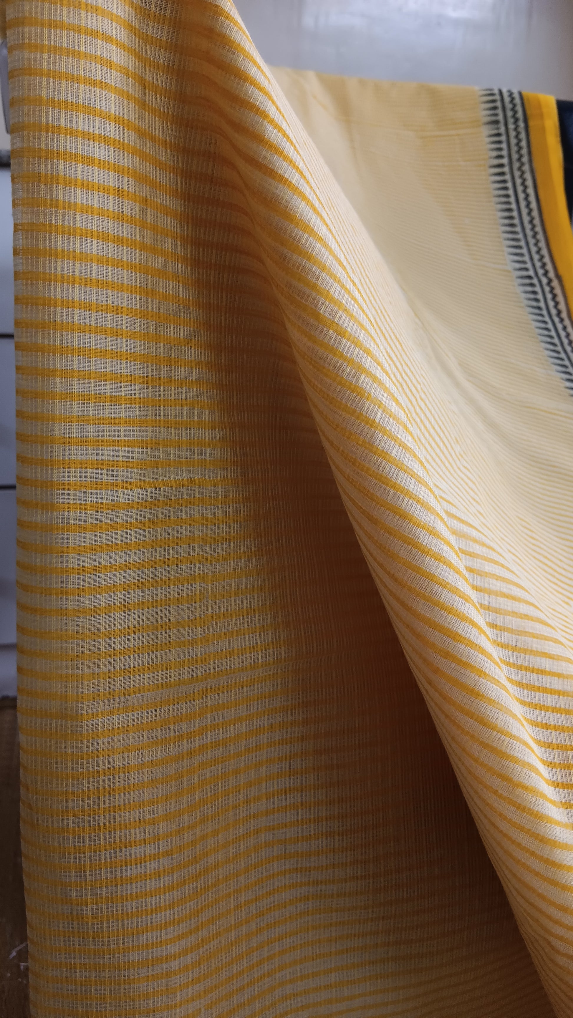 Close up view of the stripes block printed in yellow on the body of a daily wear kota cotton saree